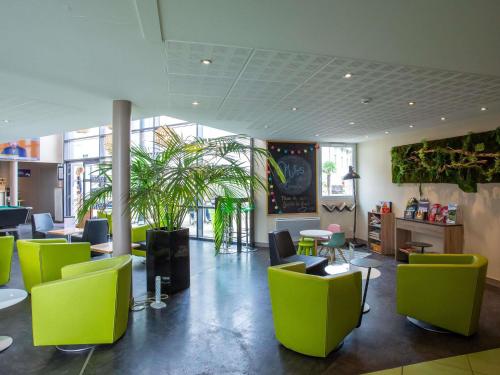 a lobby with green chairs and tables and plants at Hôtel Ibis Styles Bourges - Piscine extérieure chauffée - Restaurants à proximité in Bourges