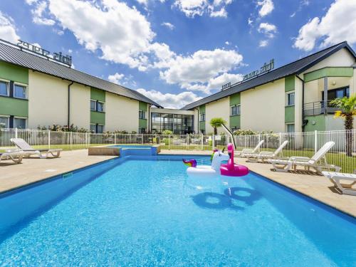 a swimming pool in front of a building at Hôtel Ibis Styles Bourges - Piscine extérieure chauffée - Restaurants à proximité in Bourges