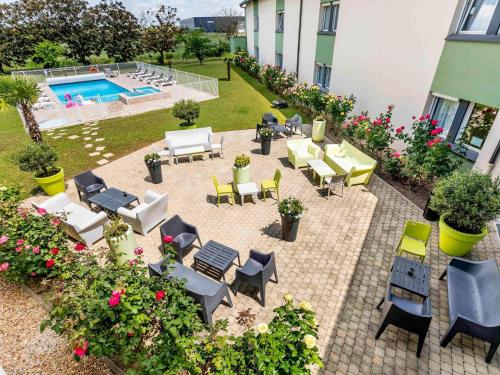 an outdoor patio with tables and chairs and a pool at Hôtel Ibis Styles Bourges - Piscine extérieure chauffée - Restaurants à proximité in Bourges