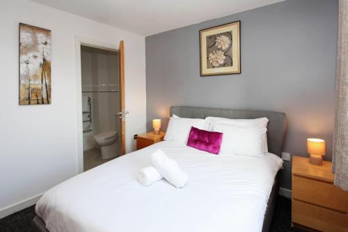 a bedroom with a large white bed with purple pillows at Albion Street Apartments in Wolverhampton