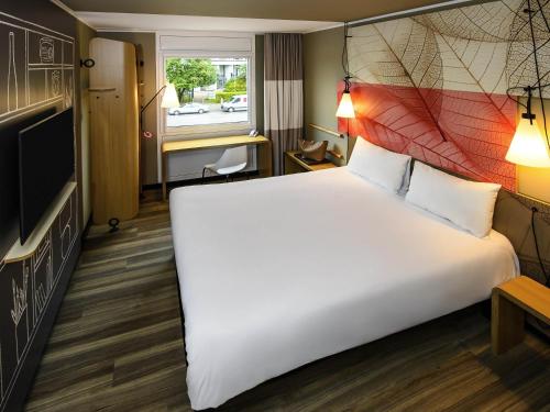 a hotel room with a large bed and a tv at ibis Hotel Muenchen City West in Munich