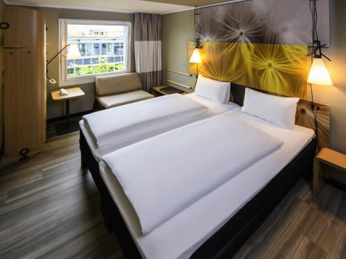 a hotel room with a large bed and a chair at ibis Hotel Muenchen City West in Munich