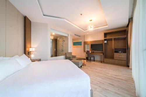 a bedroom with a white bed and a living room at Coastal Charm Panorama Bayview in Nha Trang