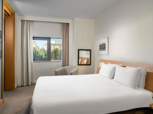 a hotel room with a large white bed and a window at Novotel Kayseri in Kayseri