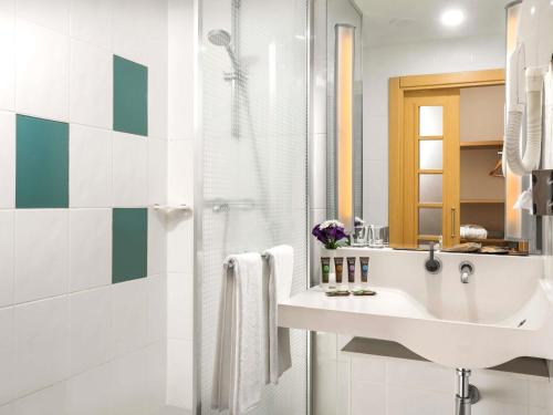 a white bathroom with a sink and a shower at Novotel Kayseri in Kayseri