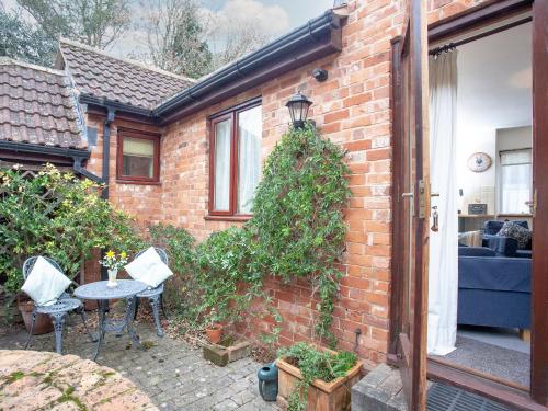 a brick house with a patio with a table and chairs at The Stables in Clyst Saint Mary
