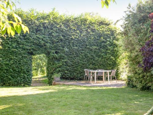 a table and chairs sitting under a hedge at The Stables in Clyst Saint Mary