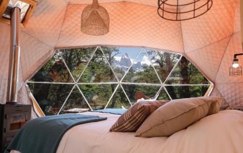 a bed in a tent with a large window at Chalten Camp - Glamping with a view in El Chalten