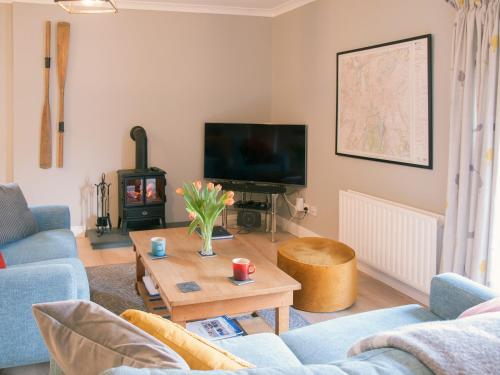 Una sala de estar con un sofá, un televisor y una mesa. en Swallows Nest, en Windermere