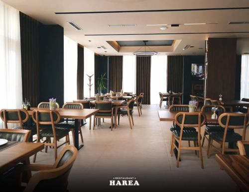 a restaurant with wooden tables and chairs and windows at Hotel & Restaurant HAREA in Suharekë