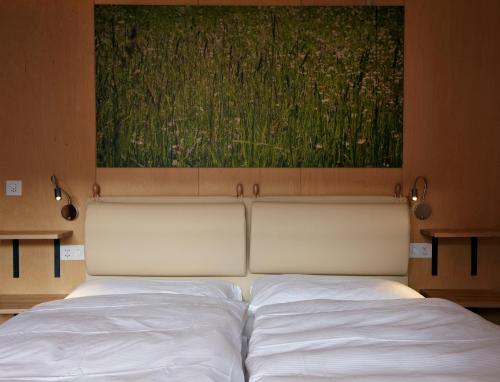 a white bed with a painting above it at Chalet Annelis Apartments in Zermatt
