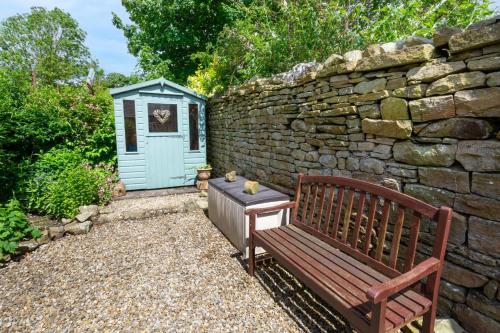 a bench next to a stone wall with a blue shed at The Shippon in Askrigg in Askrigg