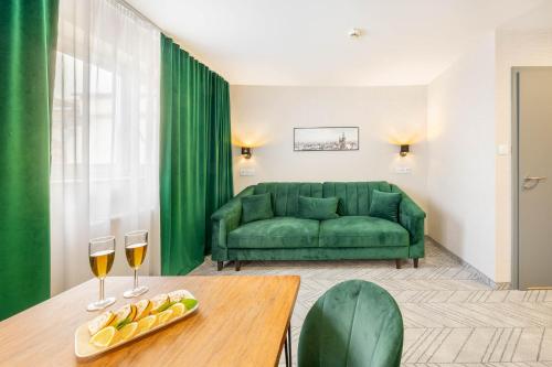 a living room with a green couch and a table with wine glasses at Hotel Polonia Centrum in Wrocław
