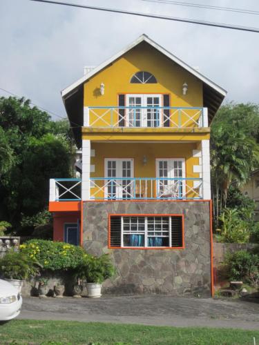 a yellow house with a balcony on top of it at Buttercup Cottage Apartments in Arnos Vale
