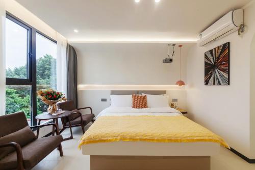 a bedroom with a bed and a chair and a window at 厦门初默民宿 in Xiamen