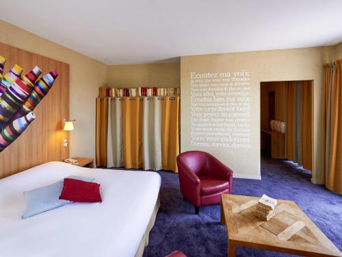 a hotel room with a bed and a chair at ibis Styles Cholet in Cholet