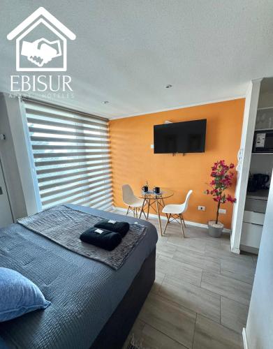 a bedroom with a bed and a table with chairs at EBISUR Apart - Hoteles CRUZ in Concepción