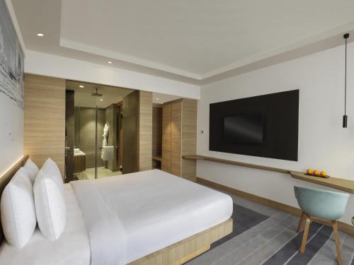 a bedroom with a white bed and a television at Novotel Mumbai Juhu Beach in Mumbai