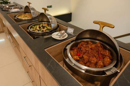 a kitchen with three pans of food on a counter at Viva Hotel Kediri, Azana Hotels Collection in Kediri