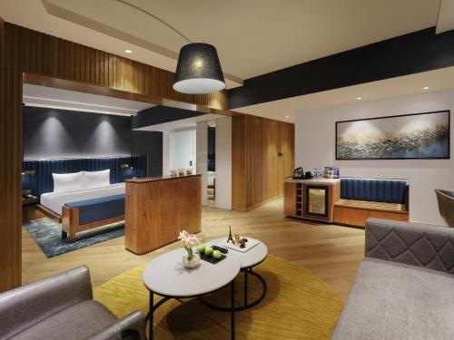 a hotel room with a bed and a living room at Novotel Mumbai Juhu Beach in Mumbai