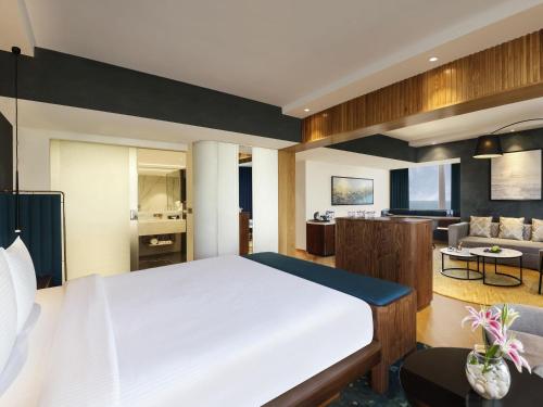 a bedroom with a large bed and a living room at Novotel Mumbai Juhu Beach in Mumbai
