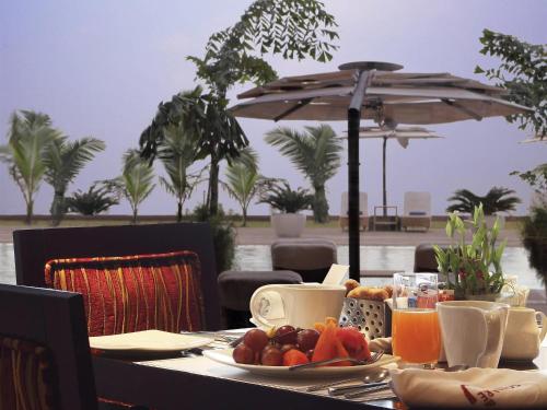 a table with a plate of fruit and an umbrella at Novotel Mumbai Juhu Beach in Mumbai