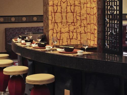 a bar in a restaurant with stools and wine glasses at Novotel Mumbai Juhu Beach in Mumbai