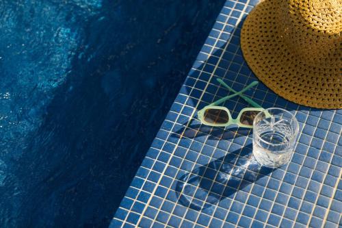 a pair of glasses and a hat next to a swimming pool at The Social Hub Barcelona Poblenou Extended Stay in Barcelona