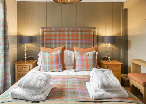 a bedroom with a bed with blankets and pillows at Thirlestane Woodland Lodges in Lauder