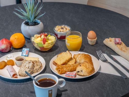 a table with two plates of breakfast foods and drinks at ibis Styles Angers Centre Gare in Angers