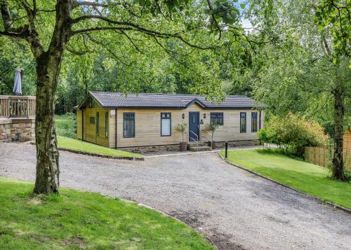 a small yellow house in the middle of a yard at Charlesworth Lodges in Glossop
