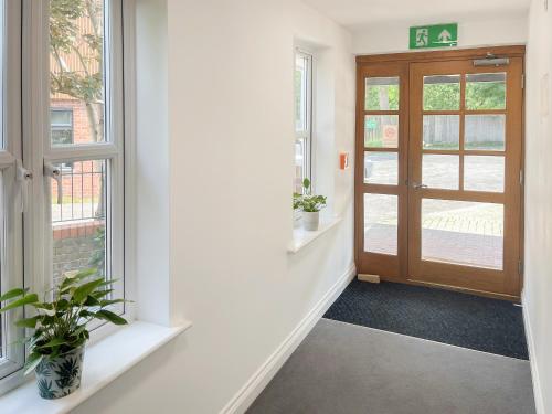 an empty hallway with a door and two potted plants at Forest Acorn in Brockenhurst
