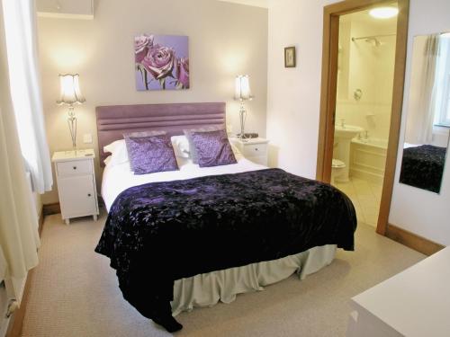 a bedroom with a large bed and a bathroom at The Coach House in Thirlmere