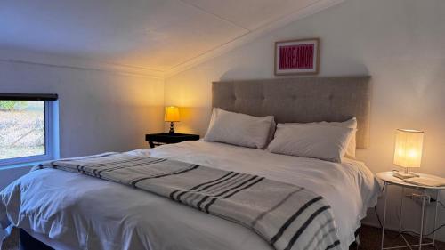 a bedroom with a large white bed with two lamps at Anamcara Villa 2, Natal Midlands Balgowan in Balgowan