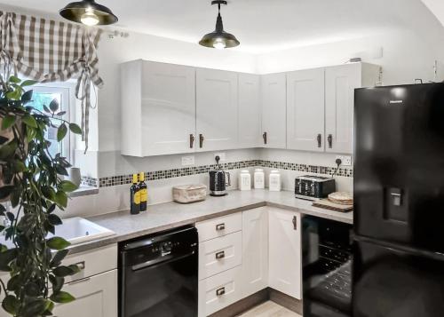 a kitchen with white cabinets and a black refrigerator at Springhouse Country Park in Slaley