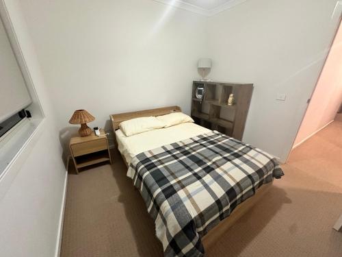 a small bedroom with a bed and a night stand at Stylish four bedroom family retreat in Saltwater Coast in Point Cook