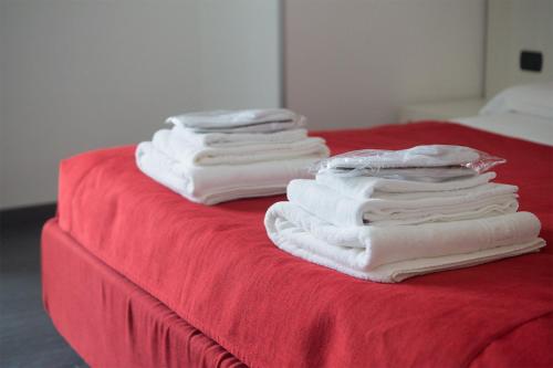 a group of white towels sitting on a red bed at Areté Luxury Room in Reggio Calabria