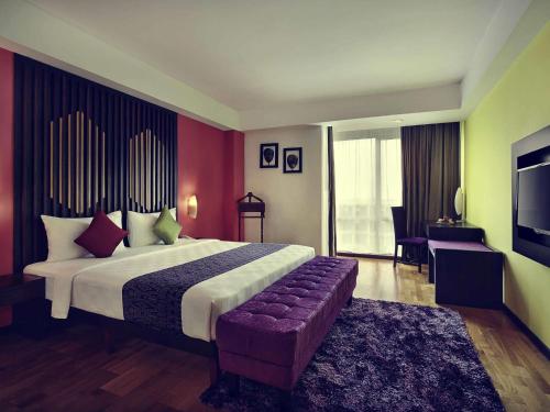 a bedroom with a large bed and a couch at Mercure Pontianak City Center in Pontianak