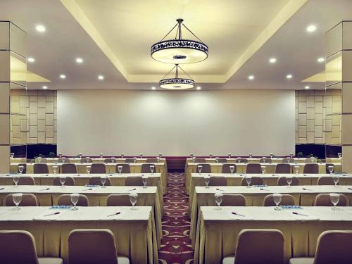 a conference room with tables and chairs and a chandelier at Mercure Pontianak City Center in Pontianak