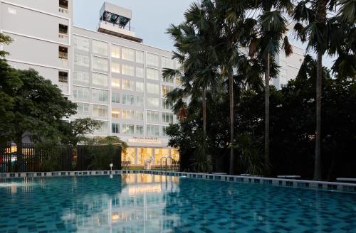 a swimming pool in front of a building at Sunday Platinum Suites in Bangkok