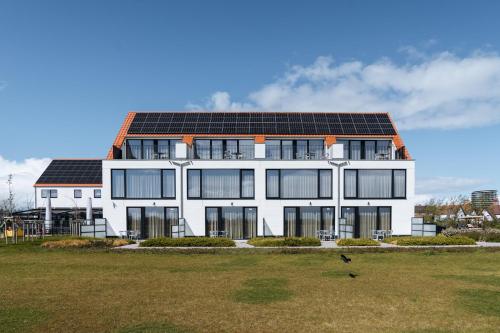 a white building with solar panels on its roof at Hotel De Zes Bochten in Knokke-Heist