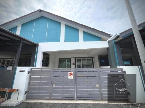 a blue and white house with a gate at Homestay Meru Ipoh Mus Lim Only Tropical White House in Ipoh