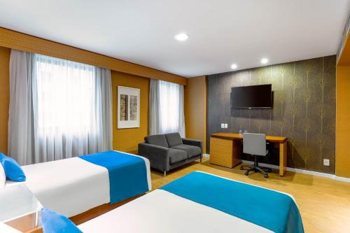 a hotel room with two beds and a desk at Wyndham Sao Paulo Ibirapuera Convention Plaza in Sao Paulo