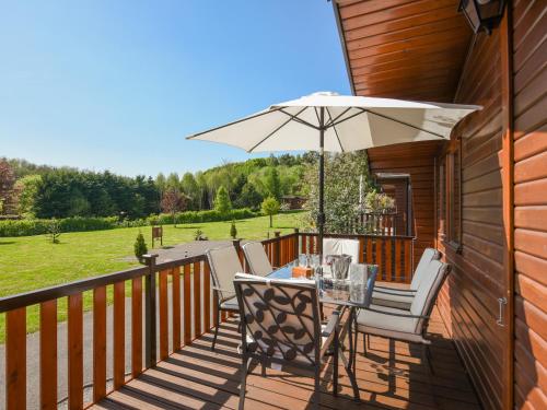 a wooden deck with a table and an umbrella at Waterfall Lodge in Eardington