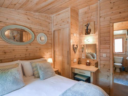 a bedroom with wooden walls and a bed and a bathroom at Waterfall Lodge in Eardington