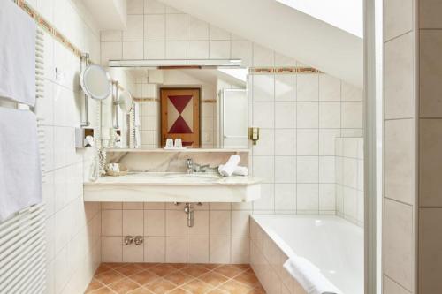 a bathroom with a tub and a sink and a mirror at Wellnesshotel Mitterwirt in Dienten am Hochkönig