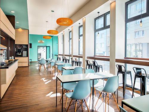 a cafeteria with tables and chairs and windows at B&B Hotel Graz-Hbf in Graz