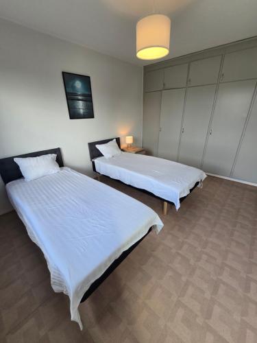 two beds in a room with white sheets at Bright Family Apartment with Balcony in Gothenburg