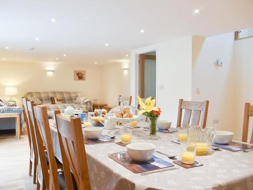 a dining room table with a white table cloth and chairs at North Barn in Monk Okehampton
