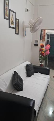 a white couch with two black pillows in a room at Diya Homestay in Rāmpur Hāt
